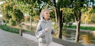 elderly woman in gray hoodie sweater jogging on pavement