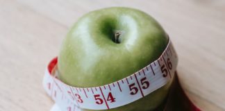 green apple with measuring tape on table in kitchen