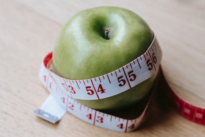 green apple with measuring tape on table in kitchen